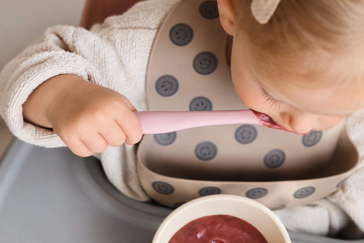 Kindje eet een eerste hapje met een roze siliconen babylepel van HeppieKids
